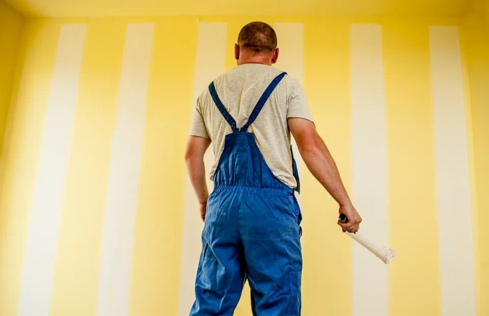 Decorator painting an interior wall with a roller